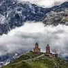 Close view of Gergeti Trinity Church near Kazbegi surrounded by mountains, popular destination to visit by rental car from Tbilisi